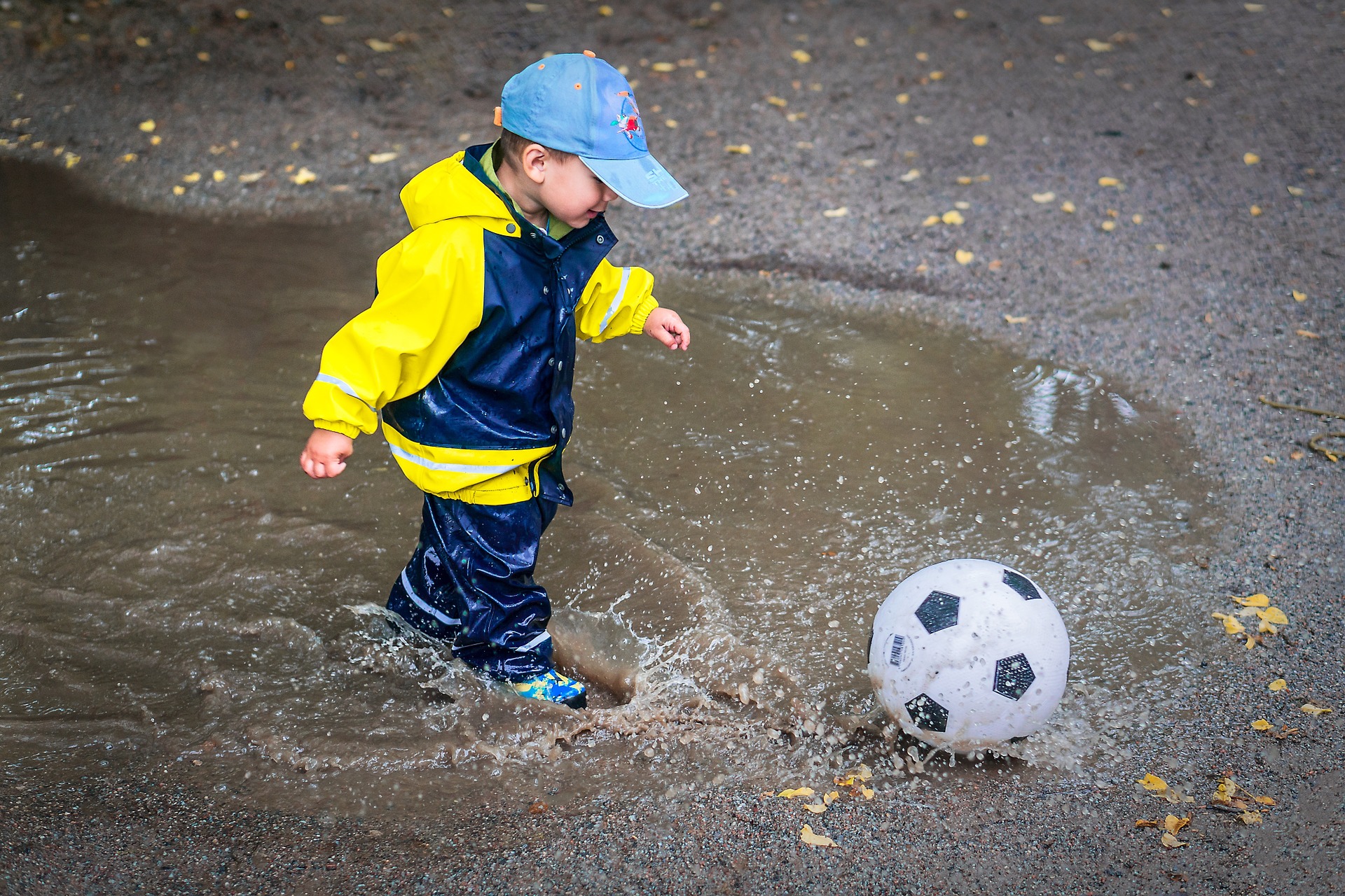 水たまりの中からボールを蹴る幼児