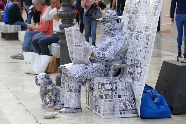 全身新聞で体を包んだ人が座っている